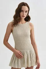 Vestido corto beige sin mangas con cuerpo de nido de abeja elástico y falda corta acampanada con vuelo.