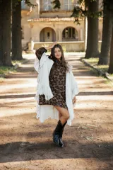 Ruana de lana merino color crudo, con diseño de silueta amplia y caída fluida. Presenta detalles de volados en lino a lo largo de la prenda y terminaciones con flecos en el ruedo.