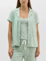 Set de pijama de tres piezas en color verde menta con estampado floral sutil, compuesto por una camisa de manga corta con botones, una musculosa básica y un pantalón largo de corte recto con cordón ajustable en la cintura.