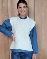 Chaleco de punto color blanco, con diseño de trenzas y rombos en el frente, cuello redondo y terminaciones acanaladas.