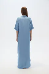 Vestido largo tipo camisero de lyocell, con cuello camisero, cierre frontal de botones, mangas cortas con dobladillo y bolsillos laterales. Presenta un corte holgado y tajos laterales en el ruedo.