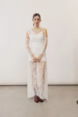 Vestido largo blanco de encaje con diseño asimétrico, tirante fino en un hombro y falda transparente.