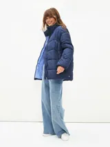 Campera puffer color blanco hueso, con cuello alto, cierre frontal con cremallera y bolsillos laterales con cierre.