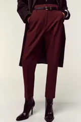 Pantalón de tiro alto y corte tobillero, confeccionado en tejido de aspecto denim oscuro. Presenta diseño de pinzas frontales, bolsillos laterales y cierre frontal con cremallera, botón y gancho. Incluye un cinturón fino a tono con hebilla metálica dorada.