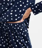 Pijama largo de plush color azul marino con estampado de lunares blancos, compuesto por una blusa de manga larga con cuello redondo y un pantalón con cintura elástica.