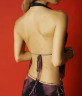 Top halter de tela liviana con estampado tie-dye en tonos morados y negros. Diseño con escote pronunciado en V, fruncido en el busto y peplum corto. Se ata al cuello y a la espalda con cordones finos.