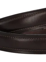 Cinturón de cuero marrón con pespuntes decorativos a tono, hebilla metálica rectangular de color plateado envejecido y pasador de cuero.