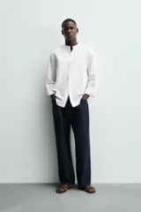 Camisa negra de lino y algodón, corte relaxed fit, cuello mao, manga larga con puños abotonados y cierre frontal con botones.