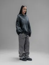 Hoodie oversize de corte crop en color gris oscuro, confeccionado en algodón rústico. Presenta un diseño con costuras expuestas, efecto de desgaste y detalles de roturas en los bordes, incluyendo puños y ruedo.