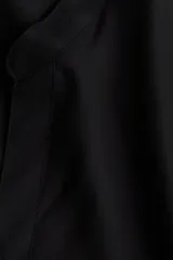 Vestido túnica de viscosa color negro, de corte holgado, largo hasta la rodilla, con cuello mao y abertura en V. Cuenta con mangas cortas, hombros caídos y aberturas laterales en el bajo.