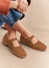 Zapato tipo guillermina de cuero color marrón, con tira en el empeine y hebilla metálica, detalle de costuras decorativas alrededor de la puntera cuadrada y suela plana.