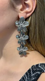 Aros colgantes de diseño floral en color plateado, compuestos por tres flores superpuestas con textura estriada y centro brillante.