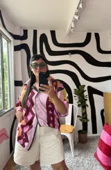 Camisa de manga corta con cuello, diseño estampado abstracto y geométrico en tonos rosados, marrones, amarillos y verdes. Cierre frontal.