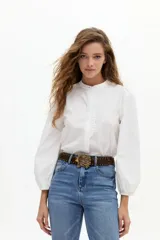 Camisa blanca de algodón con cuello mao, mangas largas abullonadas y detalle de volados en la botonera frontal.
