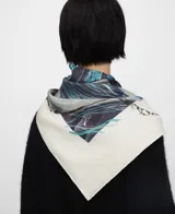 Maxi pañuelo de seda mulberry 100% firmado por Adolfo Domínguez, con diseño estampado de motivos de ajo en tonos gris, azul y turquesa sobre fondo blanco, y dobladillo hecho a mano.
