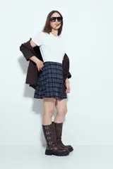 Minifalda tableada con estampado de cuadros en tonos oscuros, de corte acampanado y estilo colegial.