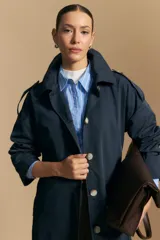 Trench azul marino de corte clásico con cuello amplio, botones frontales grandes en color beige, y detalles en los hombros.