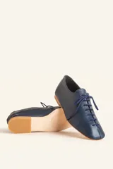 Zapato tipo oxford plano de cuero vacuno en color azul marino, con cordones al tono y suela de cuero.