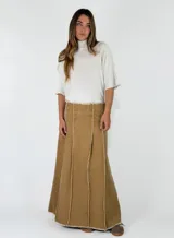 Pollera larga de denim color marrón, con diseño de paneles verticales y costuras desflecadas visibles.