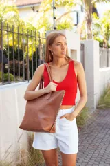 Bolso tote de cuero color tostado con costuras blancas a la vista en los laterales y doble asa de hombro.