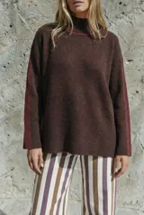 Sweater de punto con cuello alto, diseño oversize y mangas largas. Presenta un contraste de color en el cuello y una franja vertical en las mangas en tono beige.