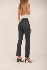 Jean de tiro alto color negro con acabado encerado, silueta slim y pierna levemente evasé.