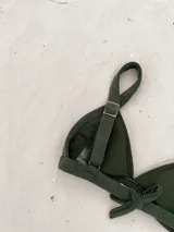 Top de bikini modelo triángulo en color lila, con textura acanalada y breteles regulables. Cuenta con forro interno y cierre mediante atadura en la espalda.