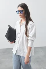 Camisa de manga larga de algodón en color blanco, con cuello clásico, cierre frontal de botones y silueta relajada.