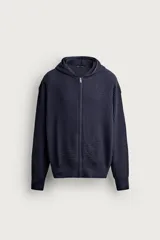 Sudadera hoodie relaxed fit color azul marino, confeccionada en tejido de algodón con estructura waffle. Cuenta con cuello con capucha, manga larga, bolsillos laterales, acabados en rib y cierre frontal con cremallera.