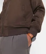 Chaqueta bomber azul marino lisa, con cierre frontal, cuello redondo y bolsillos laterales.