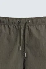 Bañador de hombre de largo medio, color celeste claro con rayas blancas horizontales. Presenta cintura elástica ajustable con cordón, bolsillos frontales y bolsillos traseros de plastrón. Incluye forro interior.