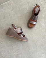 Sandalias de cuero vacuno color negro, con taco de cuña y tira ancha sobre el empeine. Ajuste con hebilla al tobillo.