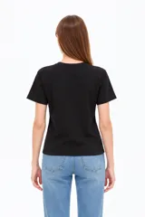 Remera negra de algodón, manga corta, con cuello redondo y diseño gráfico estampado en el pecho que incluye un sol, flores y la leyenda 'Since 1973'.