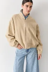 Campera bomber de paño color beige, con cierre frontal, cuello alto y puños elásticos.