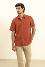 Camisa sport de manga corta, confeccionada en una mezcla de lino y algodón. Presenta cuello clásico, cierre frontal con botones de coco y un bolsillo aplicado en el pecho.