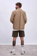 Cazadora color beige con cuello clásico, cierre frontal con botones, mangas largas y bolsillos de parche en el pecho.