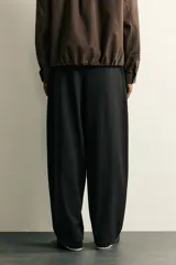 Pantalón de corte balloon fit confeccionado en tejido con viscosa. Presenta cintura ajustable con cinturón integrado, pliegues frontales, bolsillos laterales y bolsillos traseros de doble vivo. Cierre frontal con cremallera y botón.