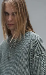 Sweater de cuello redondo con diseño de tejido texturizado en color verde y blanco. Presenta un calce relajado y terminaciones en punto rib en el cuello.