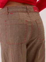 Pantalon de corte recto con costuras verticales decorativas en contraste color rojo. Presenta cintura con trabillas, cierre frontal con botón y bolsillos laterales.