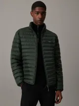 Campera puffer Calvin Klein color verde oscuro, con cuello alto, cierre frontal con cremallera, bolsillos laterales y logo de la marca en el pecho.