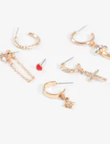 Set de aros plateados con diferentes diseños: un aro tipo pin con detalle rosa, un aro con cadena colgante, dos aros tipo argolla (uno liso y otro texturizado), un aro con dije de hongo multicolor y un aro con dije de cruz.