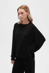 Buzo negro de punto canalé, corte holgado, cuello redondo y mangas largas.