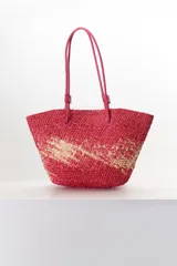 Bolso tipo shopper de paja trenzada color rosa con detalles en beige. Tiene doble asa de cuero sintético color fucsia.