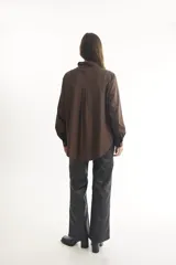 Camisa color beige de corte clásico con cuello, mangas largas y bolsillo frontal.