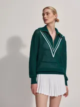 Sweater de punto verde oscuro con cierre dorado y cuello polo. Presenta un diseño en V blanco en el pecho.