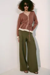 Chaqueta de punto color marrón con detalles en tono marfil en el escote en V, los puños y el ruedo. Cuenta con manga larga, cierre frontal con botones y un cinturón fino ajustable del mismo tejido.