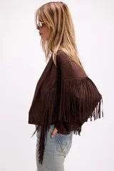 Chaqueta de efecto gamuza en color marrón, con solapas amplias, cierre frontal con botón y flecos largos decorativos en la parte frontal y trasera. Presenta un diseño estructurado de estilo western.