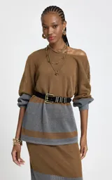 Sweater de punto calado con diseño de bloques de color en tonos marrón y gris. Presenta escote barco, mangas largas con puños ajustados en color gris y corte recto.