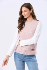 Chaleco tejido de punto grueso en color beige, con cuello redondo y diseño estructurado con detalles de trenzas verticales. Presenta un pequeño aplique de cuero sintético en la parte inferior.