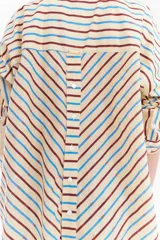 Camisa oversize de algodón con estampado de rayas multicolor en distintas direcciones, cuello camisero, mangas largas y detalle de botonera vertical en la espalda.